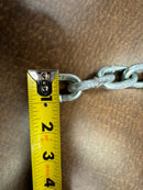 Close-up of a single link from a new 1/4 inch Grade 30 tow chain, with a caliper measuring its width.